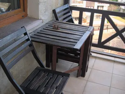 a wooden bench and a wooden table and chair on a balcony at ParkView Complex Large Flat Next to Ski Lift in Bansko