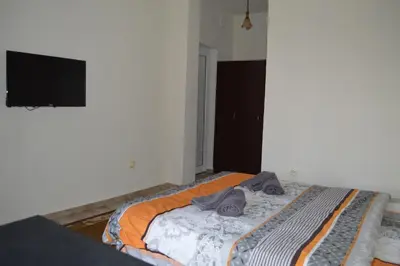 a bed in a room with a tv on the wall at Dionis Hotel in Petrich