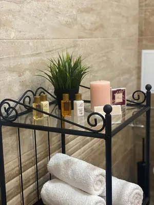 a glass shelf with towels and candles in a bathroom at Green park Sandanski in Sandanski