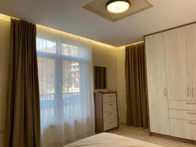 a bedroom with a large window next to a dresser and a dresser at Green park Sandanski in Sandanski