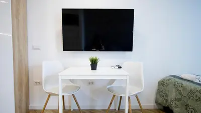 a white table with two chairs and a tv on a wall at Colonel apartment Bijou in Sofia