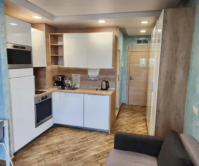 a kitchen with white cabinets and a couch in a room at Colonel apartment Relax in Sofia