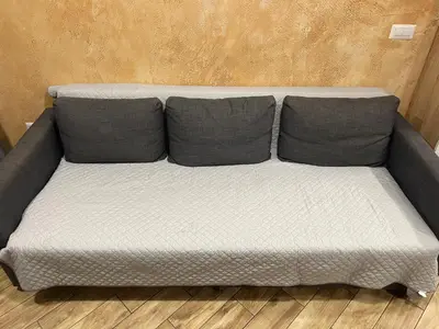 a gray couch with two pillows on a wooden floor at Colonel apartment Royal in Sofia