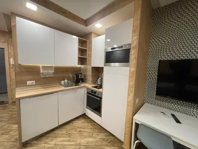 a kitchen with white cabinets and a flat screen tv at Colonel apartment Royal in Sofia