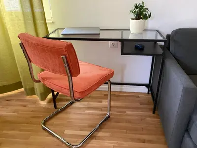 a glass desk with a chair next to a couch at Orfey Apartment in Sofia