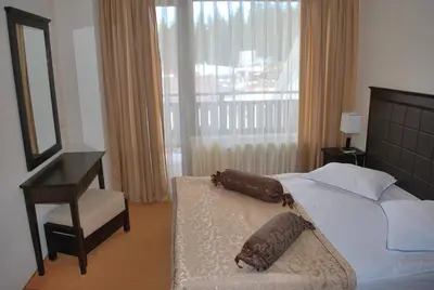 a bedroom with a bed and a chair and a mirror at Spider House Aparthotel in Pamporovo
