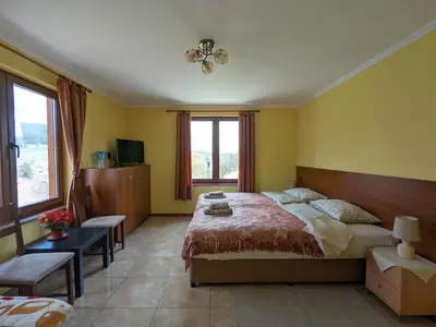 a bedroom with a large bed and a large window at Къща за гости Феникс in Koprivshtitsa