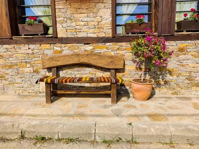 a wooden bench sitting in front of a stone wall at Rimovata Kashta Guest House in Leshten