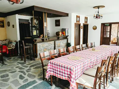 a dining room with a table and chairs and a fireplace at Rimovata Kashta Guest House in Leshten