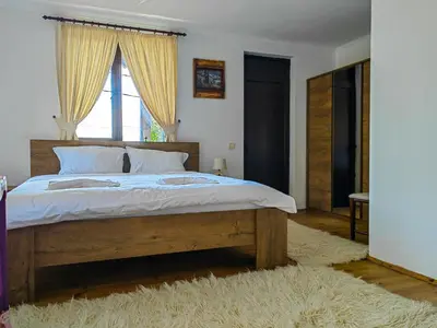 a bedroom with a large wooden bed with a window at Rimovata Kashta Guest House in Leshten
