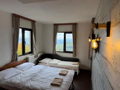 two beds in a room with two windows at Александрова вила 1 in Zlatograd