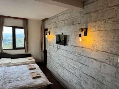 a bedroom with two beds and a stone wall at Александрова вила 1 in Zlatograd