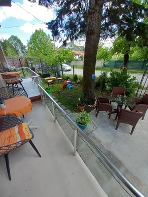 a balcony with a table and chairs and a tree at Стаи за гости - Цветето на Ангела in Bankya