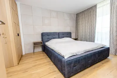 a bedroom with a bed with a blue head board at апартаменти Пасажио in Sandanski