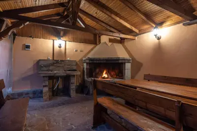 a large room with a fireplace and a wooden bench at Вили Тихия Кът in Ribarica