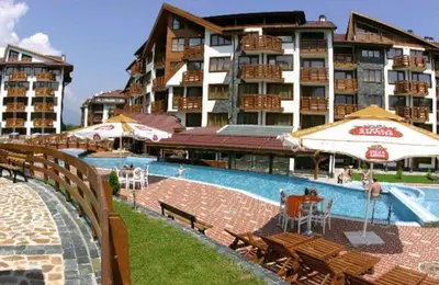 a hotel with a swimming pool with chairs and umbrellas at Apartment in Belvedere Club G205 in Bansko