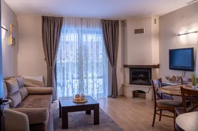 a living room with a couch and a television and a table at Вила 11 - семейна почивка в сърцето на Балкана in Ribarica