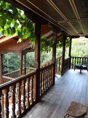 a porch with a wooden railing and a bench on it at Недкова къща in Koprivshtitsa