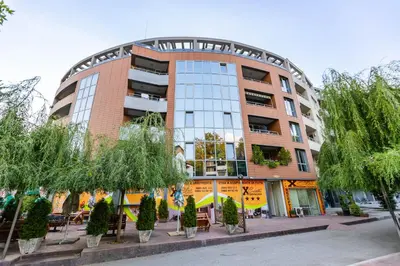 a building with tables and trees in front of it at Мезонет Пасажио in Sandanski