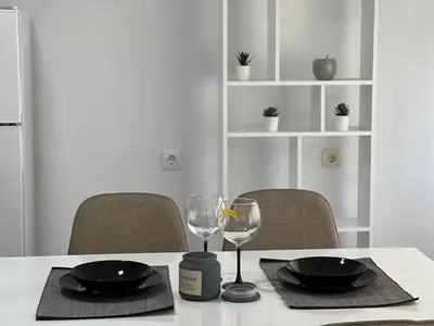 a table with two plates and two glasses on it at Апартамент Панорама Рози in Sandanski