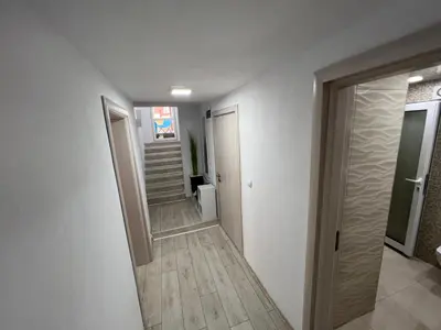 a hallway with white walls and wooden floors and a door at Апартамент Панорама Рози in Sandanski
