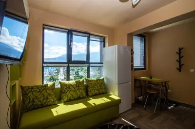 a living room with a green couch and windows at Vitosha View Apartment with Parking in Sofia