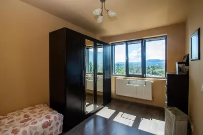 a bedroom with a bed and a large window at Vitosha View Apartment with Parking in Sofia