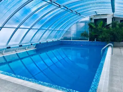 an indoor swimming pool with a glass ceiling at ENIS Hotel със закрит и отоплен минерален басейн in Sapareva Banya