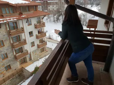 a woman standing on a balcony looking out at the snow at Mountain View Resort - Apartment B45 in Bansko
