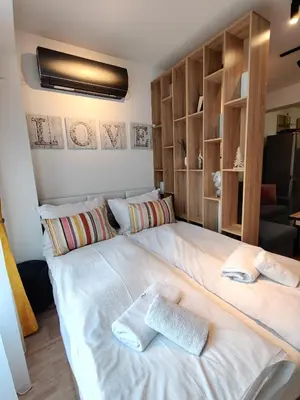 a bedroom with a large white bed with wooden shelves at Cozy Studio near the Historical Heart of Sofia by Flat Mаnager in Sofia