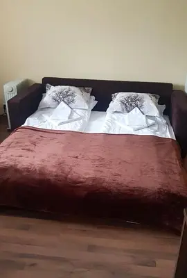 a bed with a red blanket and two pillows on it at Penthouse at Dream Bansko in Bansko