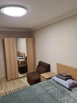 a bedroom with a bed and a chair and a mirror at Апартамен в Манастира 3 in Smolyan