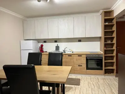 a kitchen with a wooden table with chairs and a refrigerator at Апартамен в Манастира 3 in Smolyan