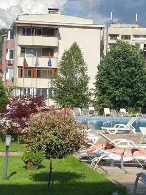 a resort with a pool and chairs and a building at Апартамент за гости in Devin
