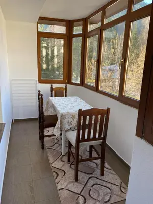 a dining room with a table and chairs and windows at Апартамент за гости in Devin