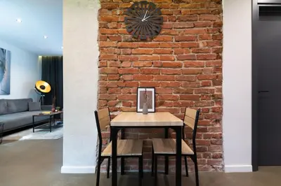a brick wall in a living room with a table and chairs at Lozenets Modern Apartment Tranquil & Central in Sofia