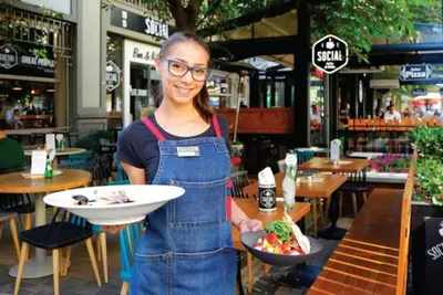 a woman holding a plate of food in a restaurant at Top Center Studio 1 in Sofia