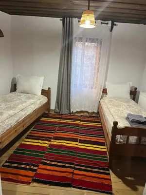 a bedroom with two beds and a rug on the floor at Къща за гости Близнаците in Leshten