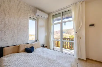 a bedroom with a bed and a large window at Вила Ибър село Радуил in Raduil