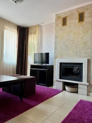 a living room with a fireplace and a flat screen tv at Гранд Манастира частен апартамент in Pamporovo