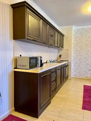 a kitchen with brown cabinets and a microwave at Гранд Манастира частен апартамент in Pamporovo