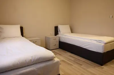 a bedroom with two beds with white sheets and wooden floors at Hotel Leda in Sofia