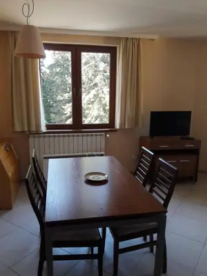 a dining room with a wooden table and chairs at Apartment 322, Villa Park in Borovets