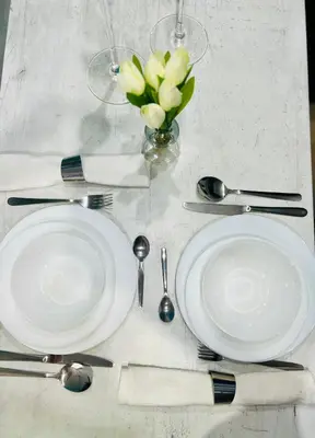 a table with white plates and silverware and a vase of flowers at Flower house 7 in Sofia