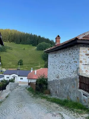 a stone building on a dirt road next to a hill at Marina apartment in Stoykite