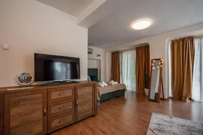 a living room with a television on a wooden dresser at Cozy studio with FRENCH WINDOWS in Plovdiv