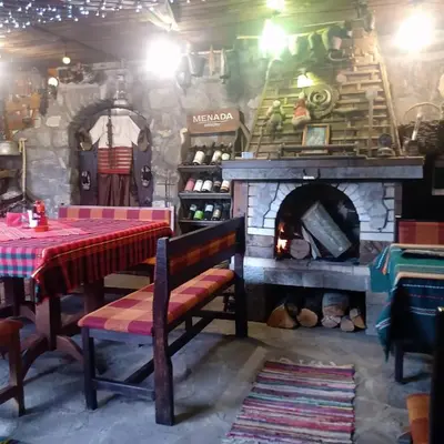 a dining room with a table and a fireplace at КръчмЪ при Байката Alpin in Ribarica