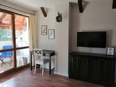 a living room with a television and a desk with a chair at Студио 