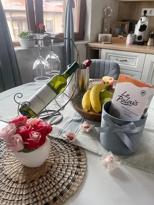 a table with a bottle of wine and a basket of fruit at Boutique apartment Bansko Bell Tower in Bansko