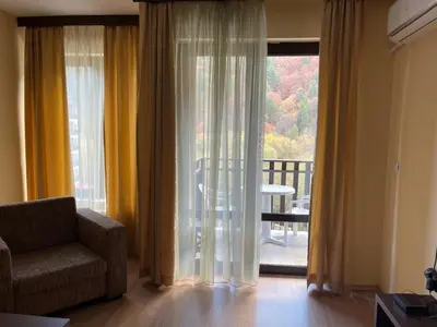 a living room with a chair and a large window at Мия 2 Спа хотел Свети Спас in Velingrad